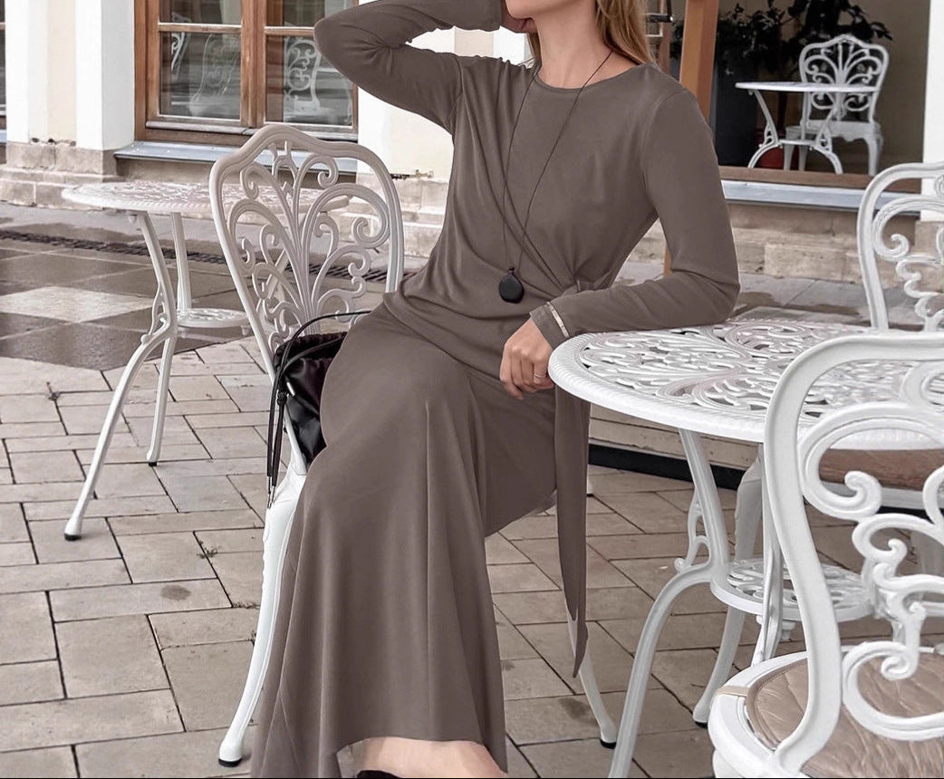 Woman in a brown dress sitting at an outdoor cafe table.