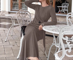 Woman in a brown dress sitting at an outdoor cafe table.