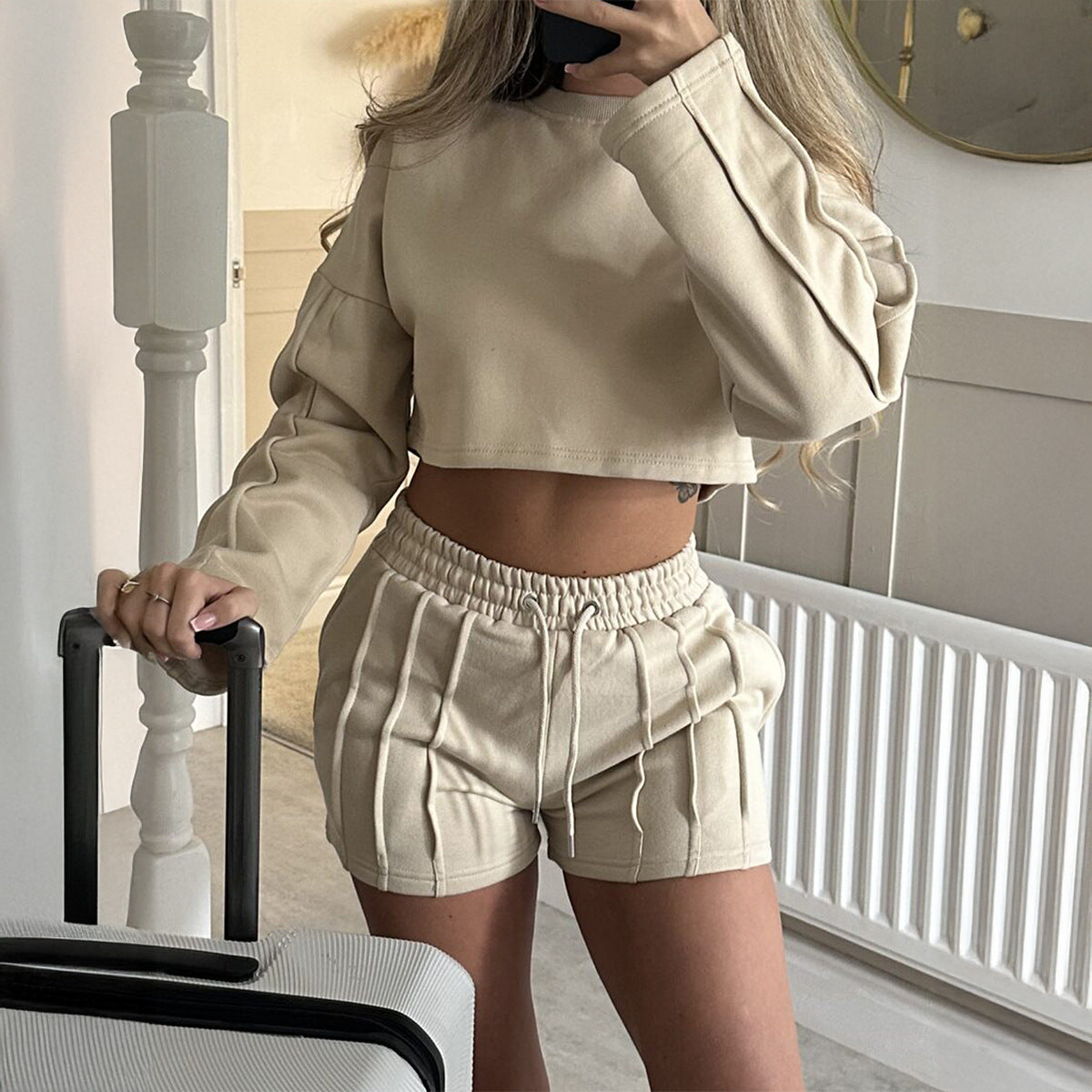 Person wearing a beige outfit with shorts and a cropped top, standing in a room.