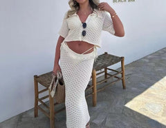 Woman in a white crochet outfit standing in front of a 'Lsola Beach Bar' sign.