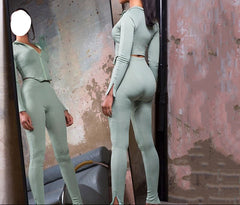 Woman in a green outfit standing in front of a mirror with a textured wall background