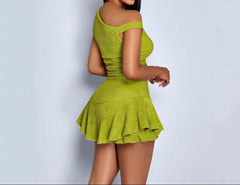 Green off-shoulder dress with ruffled skirt on a plain background