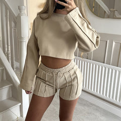 Person wearing a beige sweatshirt and shorts set in a home setting.