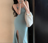 Woman in a light blue dress taking a mirror selfie with a white handbag.