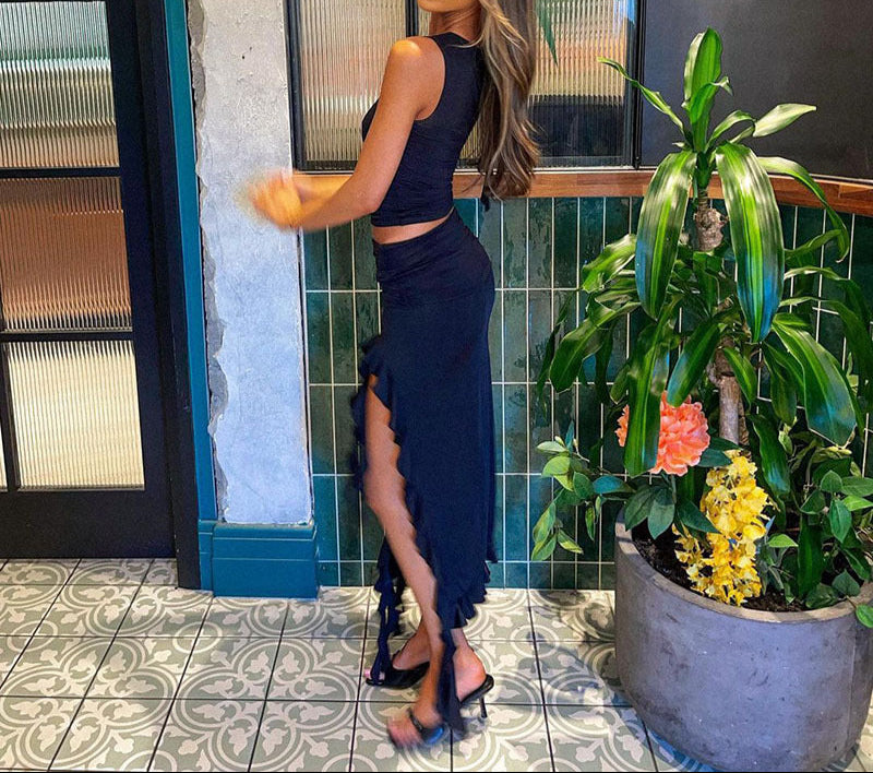 Woman in a navy blue dress standing next to a plant indoors.