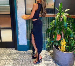 Woman in a navy blue dress standing next to a plant indoors.