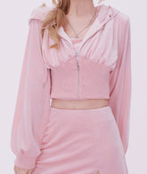 Person wearing a pink outfit with a matching jacket and skirt on a light pink background