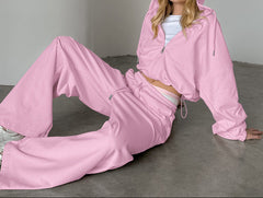 Person wearing a pink tracksuit sitting on a gray floor.