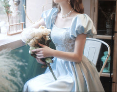 Woman in a light blue dress holding flowers indoors