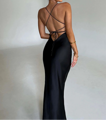 Woman wearing a black evening gown with a strappy back design on a plain background