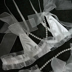 Pearl necklace draped over sheer ribbons on a black background