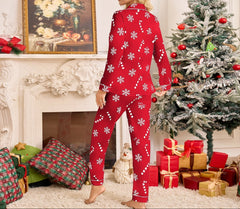 Woman in red pajamas with white patterns standing in a festive room with Christmas tree and presents.