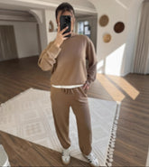 Person taking a mirror selfie wearing a brown outfit in a modern room.