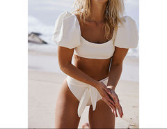 Woman in a white bikini laughing on a beach