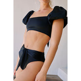 Black bikini with bow details worn by a person against a neutral background