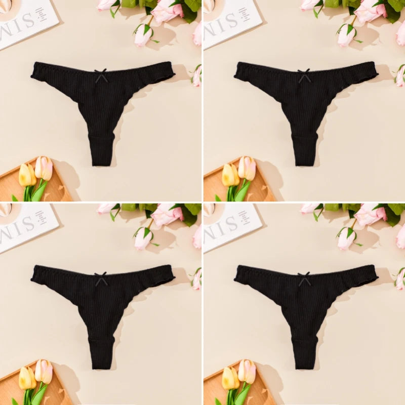 Black thong underwear displayed on a beige surface with flowers and stationery items.
