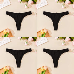 Black thong underwear displayed on a beige surface with flowers and stationery items.