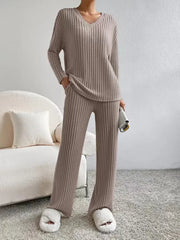 Person wearing a beige ribbed lounge set in a cozy living room.