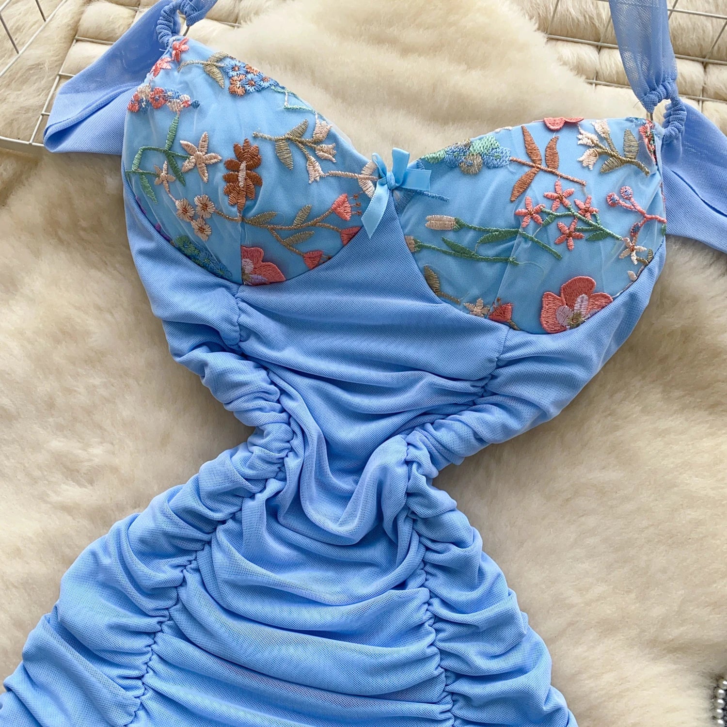 Blue mermaid tail with floral embroidery on a beige surface