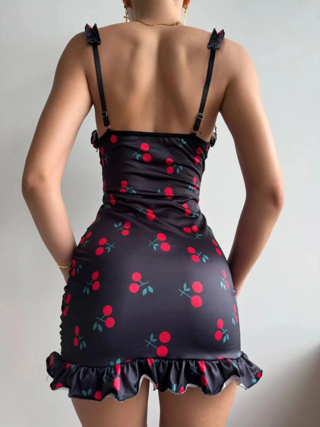 Black dress with red cherry pattern on a plain background