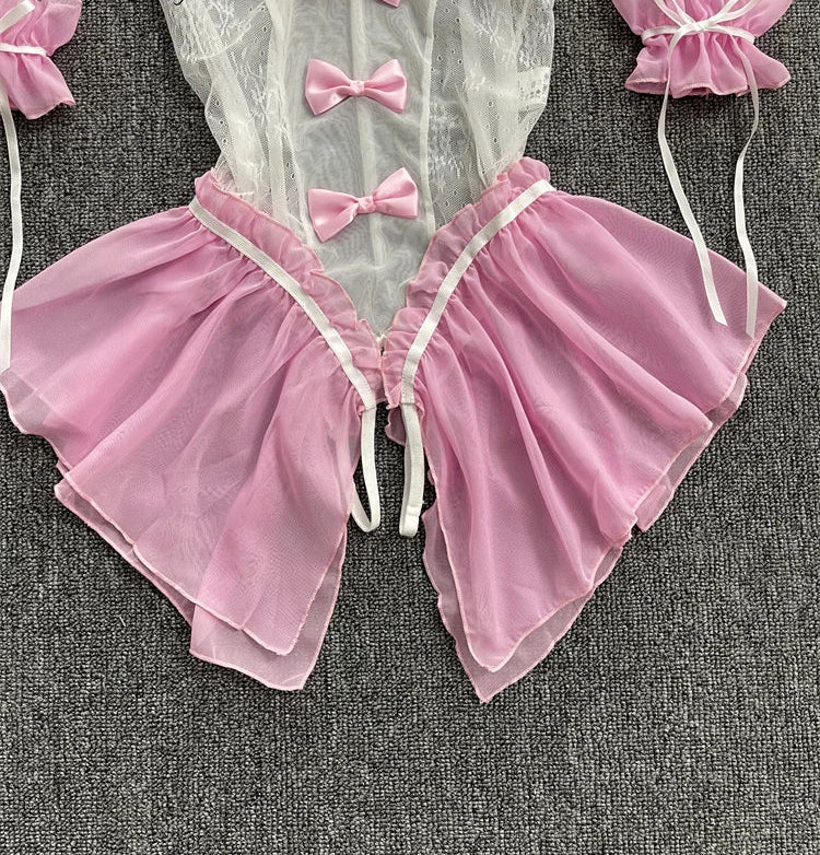 Pink and white baby outfit with ruffles and bows on a gray background