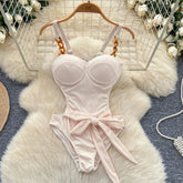 Pink swimsuit with a bow on a white fur rug with floral decorations.