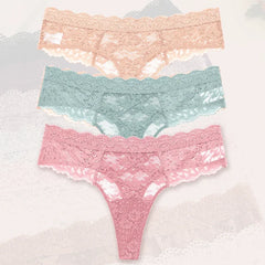 Three pairs of lace underwear in pink, green, and blue on a textured white background.