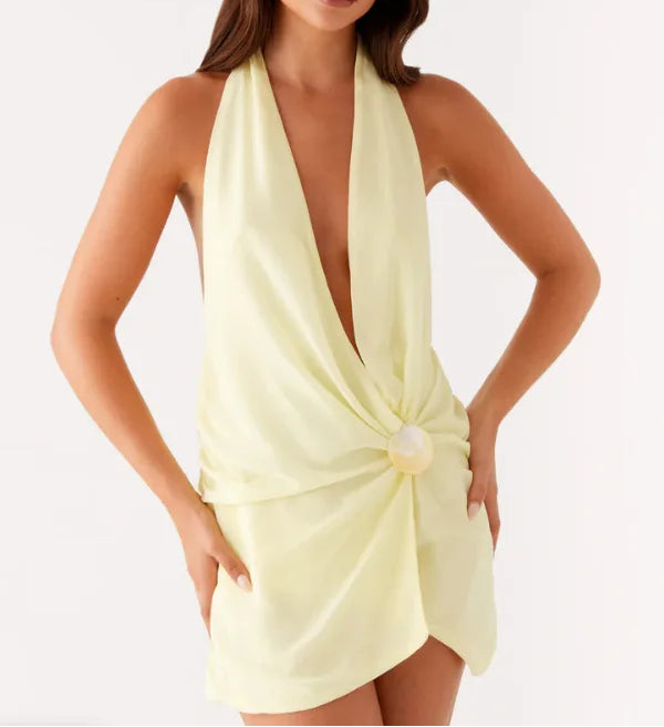 Woman wearing a light yellow halter neck dress on a white background