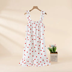 White dress with red heart patterns on a hanger against a beige background