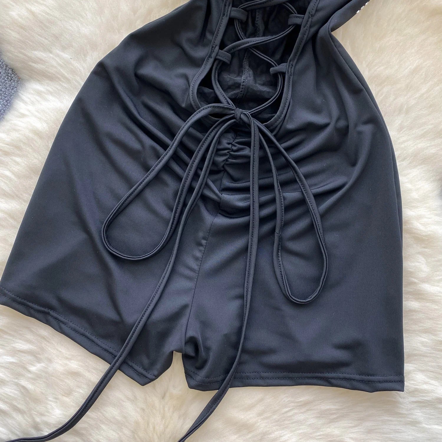 Black swimsuit top with drawstring on a light brown surface