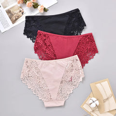 Three pairs of lace-trimmed panties in black, red, and beige on a gray surface.