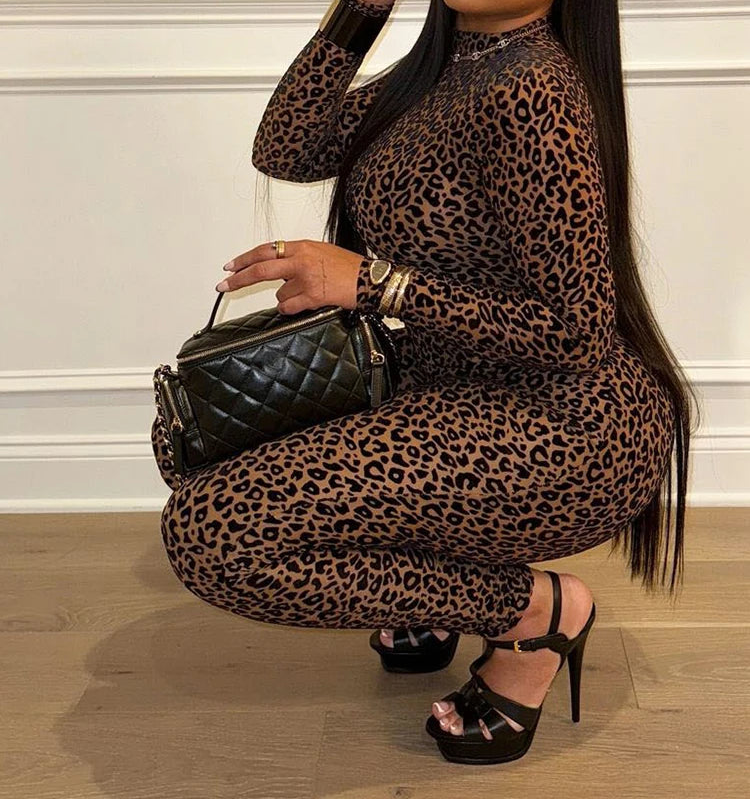 Woman in leopard print dress holding a black handbag indoors.