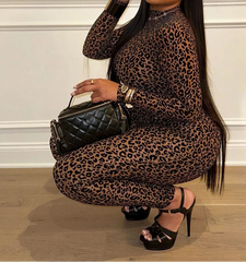 Woman in leopard print dress holding a black handbag indoors.