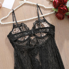 Black lace lingerie set on a wooden surface with pearls and roses.