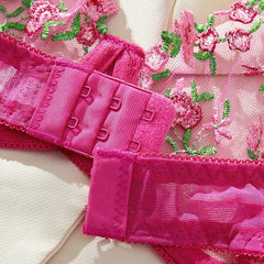 Close-up of pink lace lingerie with floral embroidery on a white background