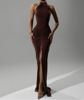 Woman wearing a brown evening gown with a high slit on a gray background