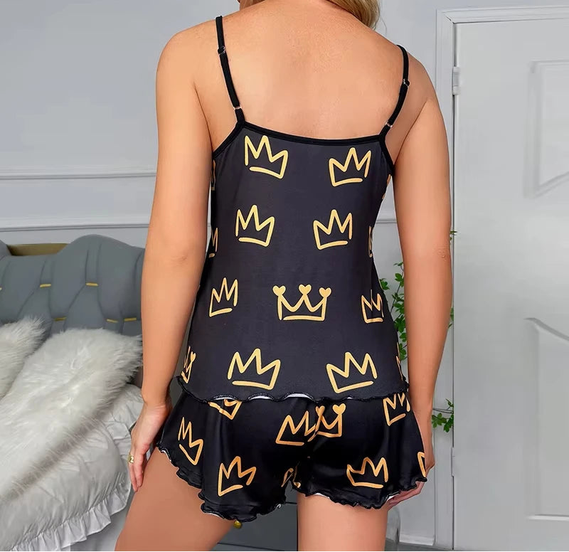 Woman wearing a black camisole and shorts with yellow crown patterns in a bedroom setting.