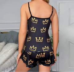 Woman wearing a black camisole and shorts with yellow crown patterns in a bedroom setting.
