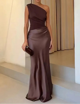 Woman in a brown one-shoulder evening gown standing on a staircase.