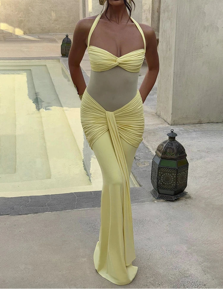 Woman wearing a yellow dress standing outdoors with a pool and lantern in the background