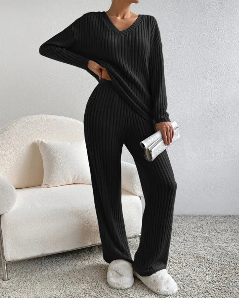 Person wearing a black ribbed lounge set in a living room.