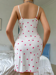 Person wearing a white dress with red heart patterns in a bedroom setting