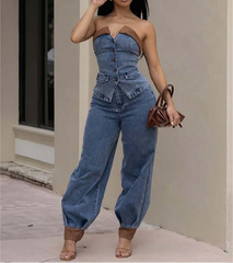 Woman wearing a denim strapless jumpsuit and sunglasses, holding a brown handbag.