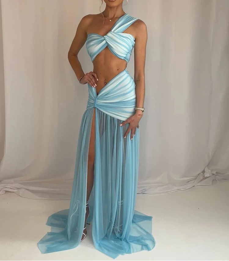 Woman wearing a light blue evening gown with a slit on a plain background