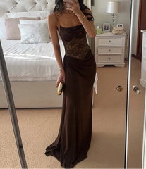 Woman in a brown evening gown taking a mirror selfie in a bedroom.