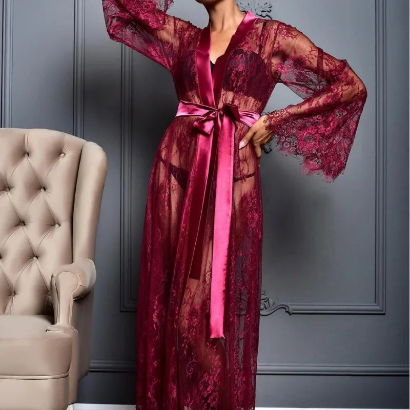 Red lace robe with a pink satin ribbon against a gray wall.