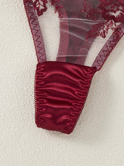 Close-up of red lace fabric with satin trim on a white background
