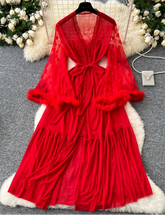 Red dress with sheer overlay on a textured surface with flowers and a hat in the background