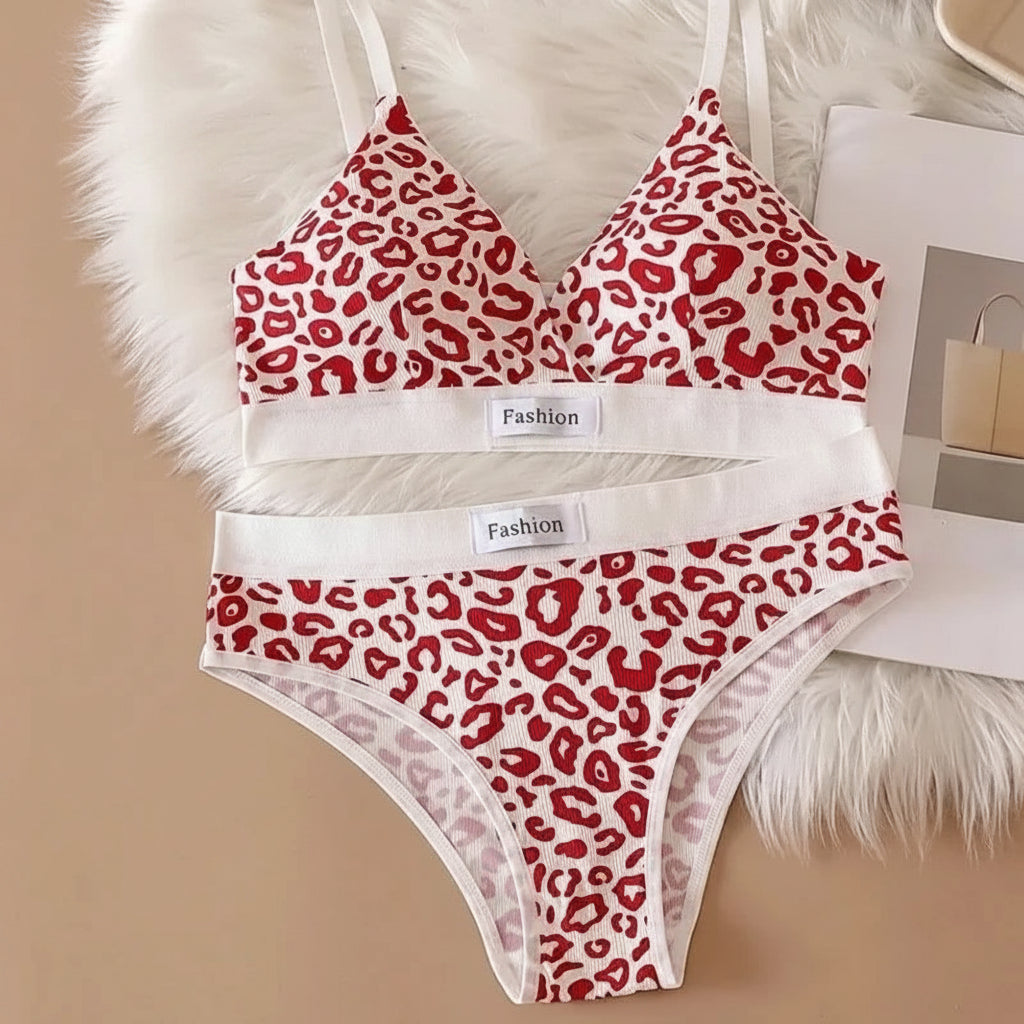 Red leopard print bra and panties set on a beige surface with a white fluffy blanket.