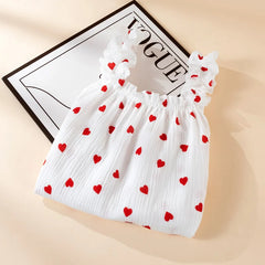 White top with red heart patterns on a beige background